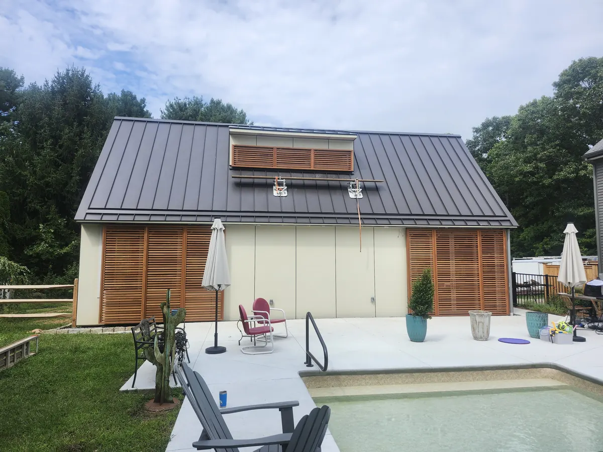 Pool house with a metal roof and cedar slat panels