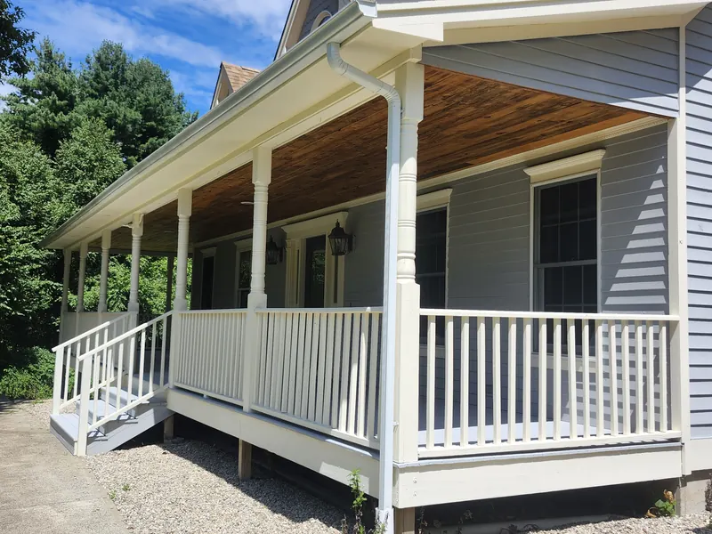 Covered wraparound porch with white rail