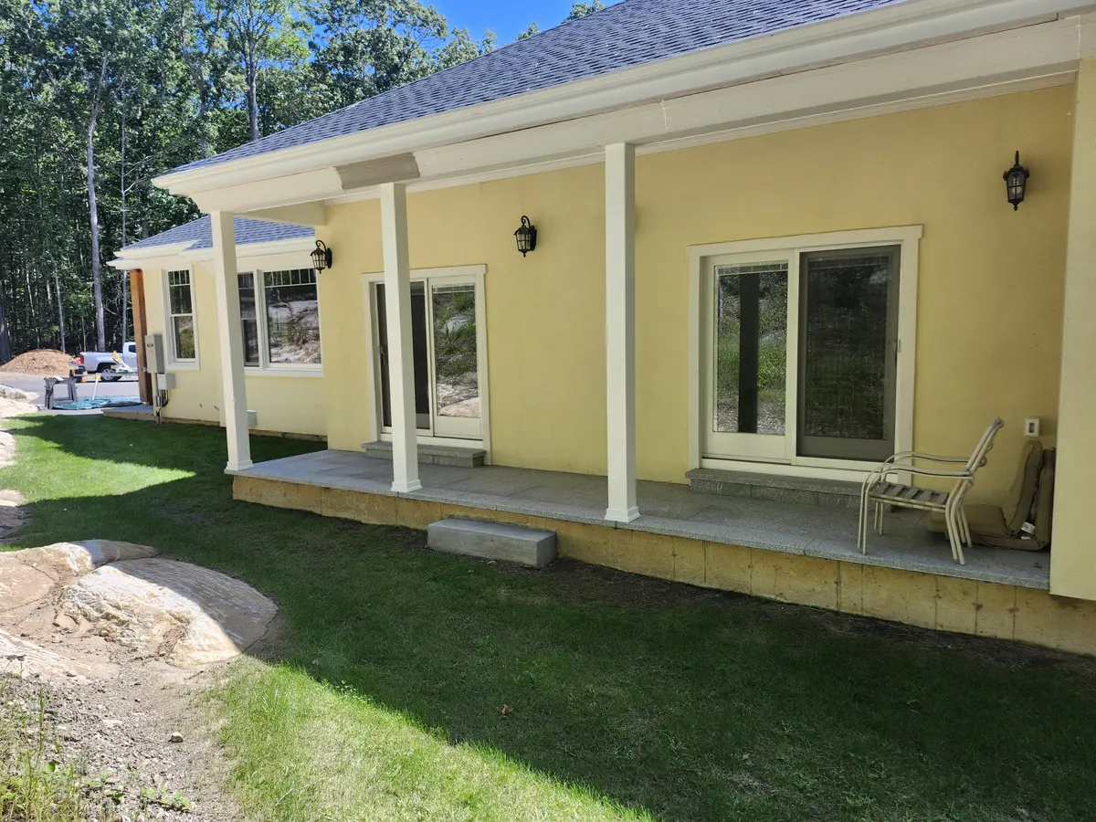 Long covered porch with square white columns on a yellow house