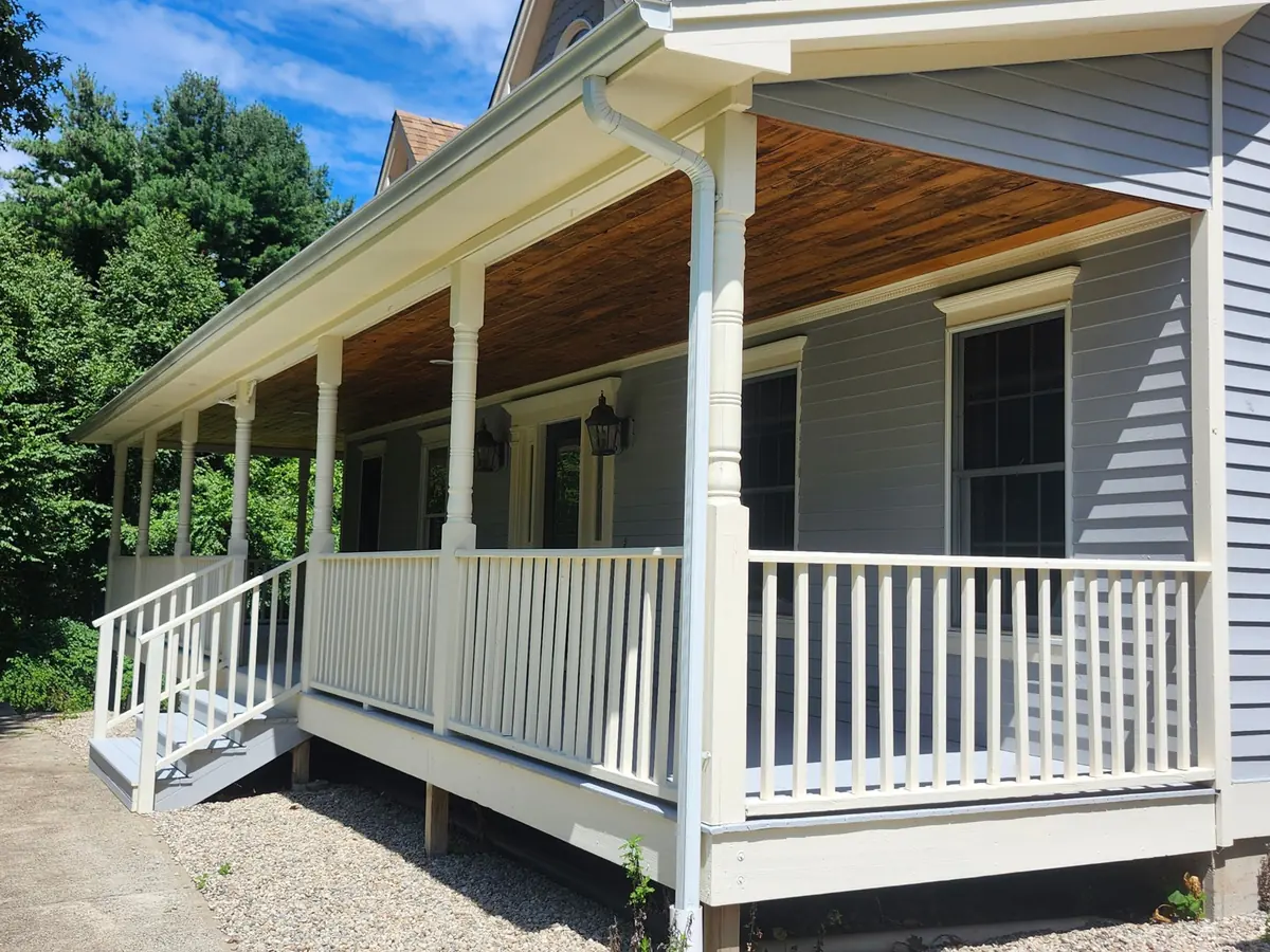 Wraparound farmhouse porch with new railings and beadboard ceiling